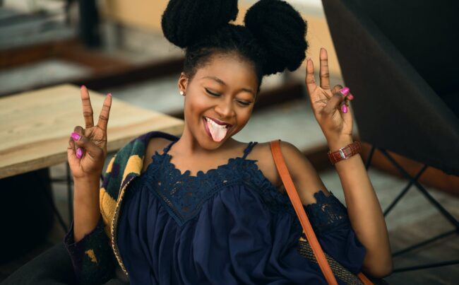 woman of colour smiling holding up two peace signs