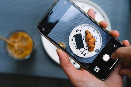 person taking a photo of food with smartphone on the table