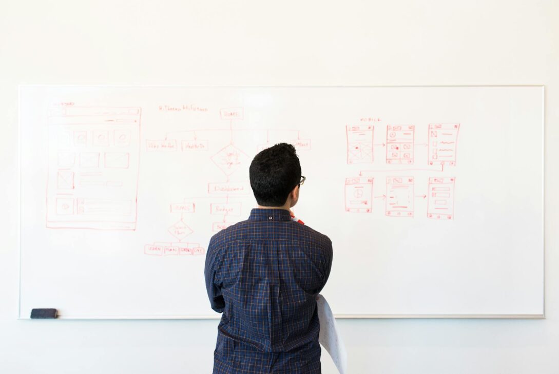 man standing in front of white board looking at ux strategy