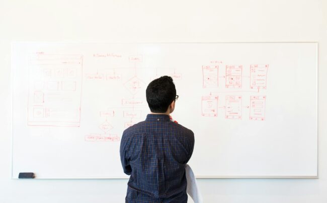 man standing in front of white board looking at ux strategy